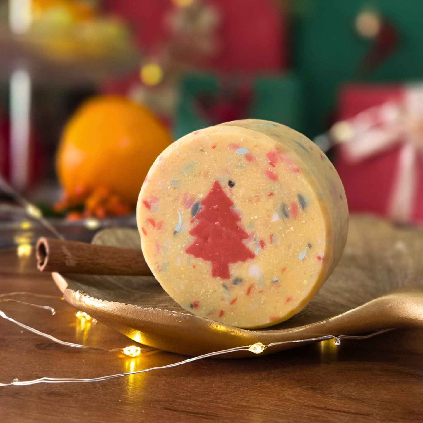 Ароматен сапун „Вълшебна Коледа“ SULLY Naturals с портокал и канела, върху златен лист и коледни светлинки.