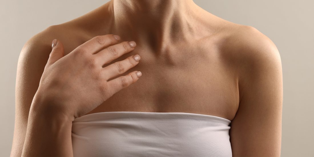 Жена докосва рамото си в баня, естествена текстура на кожата, мека светлина и усещане за сухота