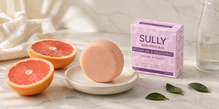 Твърд шампоан SULLY Naturals Арган и Грейпфрут за мазна коса на мраморна поставка с пресни грейпфрути и зелени листа