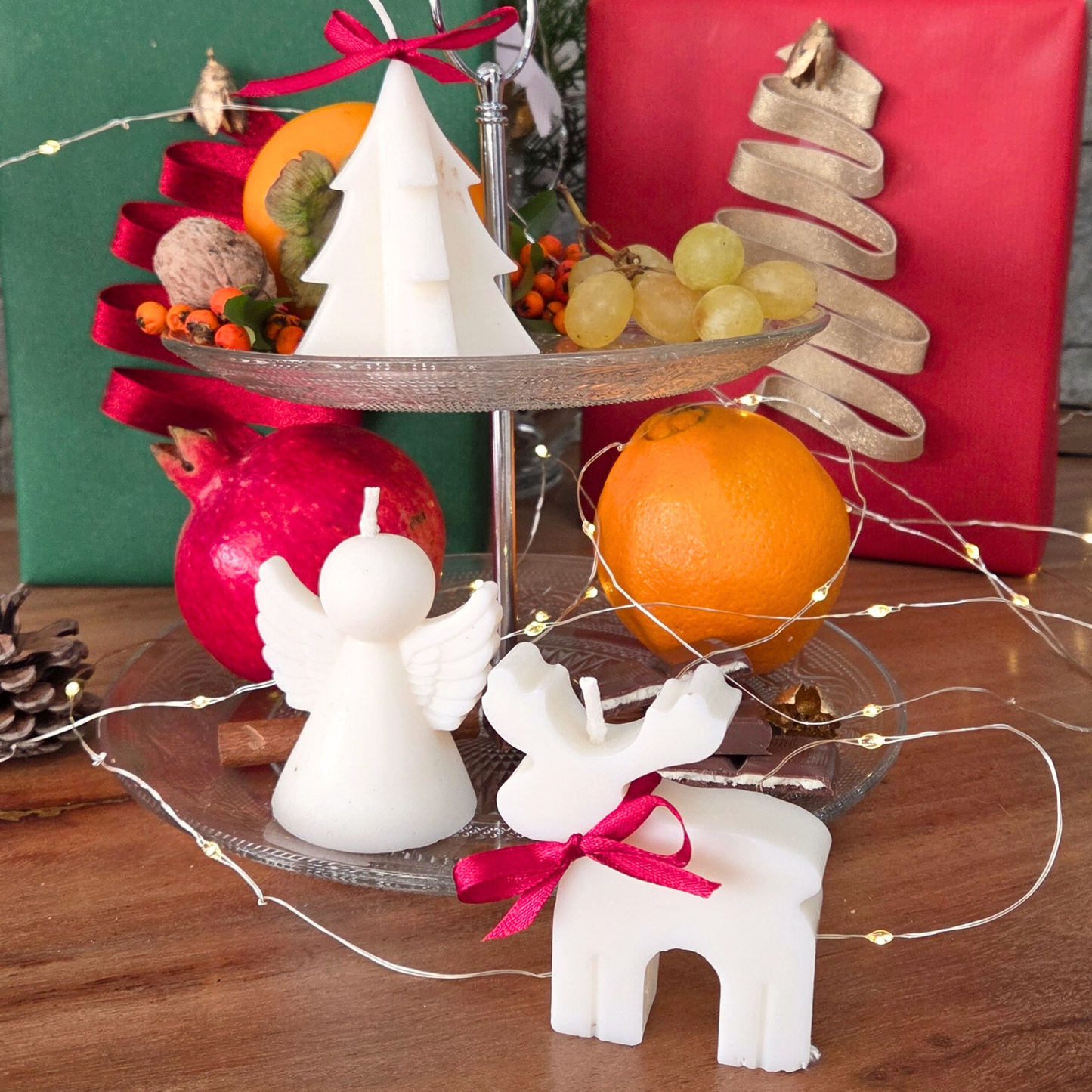 Ароматни свещи „Фигурки на празника“ SULLY Naturals подредени сред плодове, канела и празнична украса.