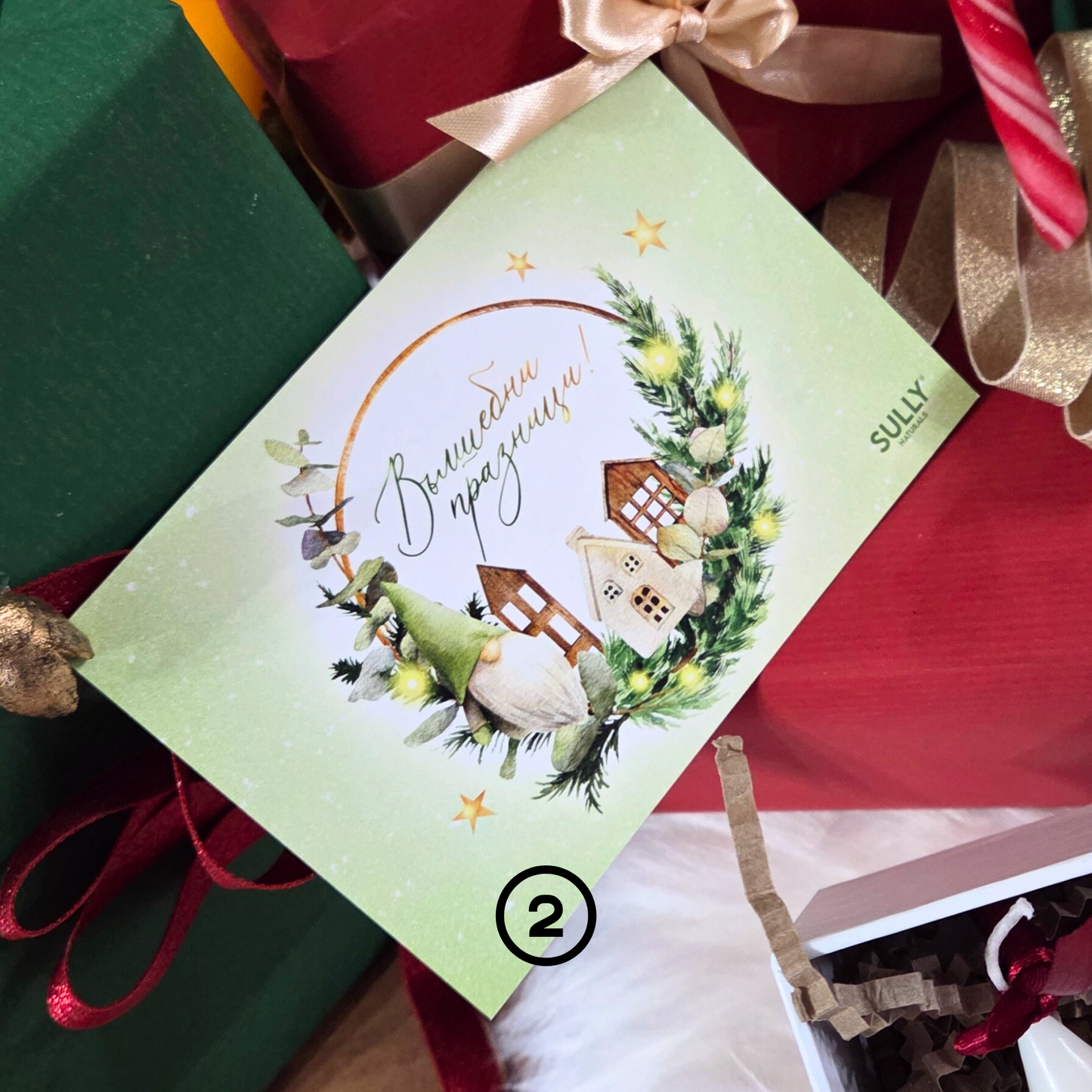 Коледна картичка „Вълшебни празници“ SULLY Naturals сред подаръци и празнична декорация, илюстрация с елхички и джудже.