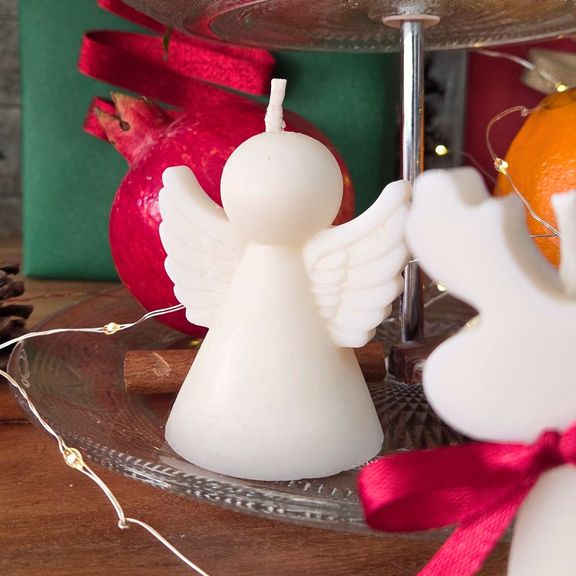 Свещ във форма на ангелче от комплекта „Фигурки на празника“, заснета сред празнична украса.