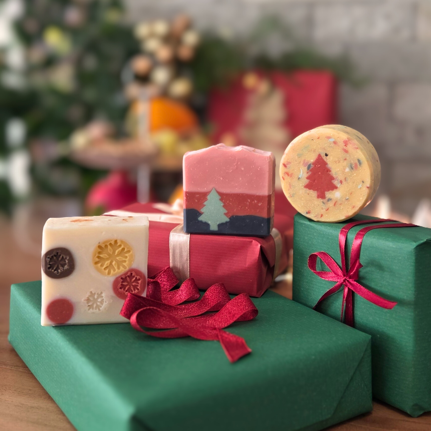 Коледно трио сапуни на SULLY Naturals, красиво подредени върху подаръци в червено и зелено.