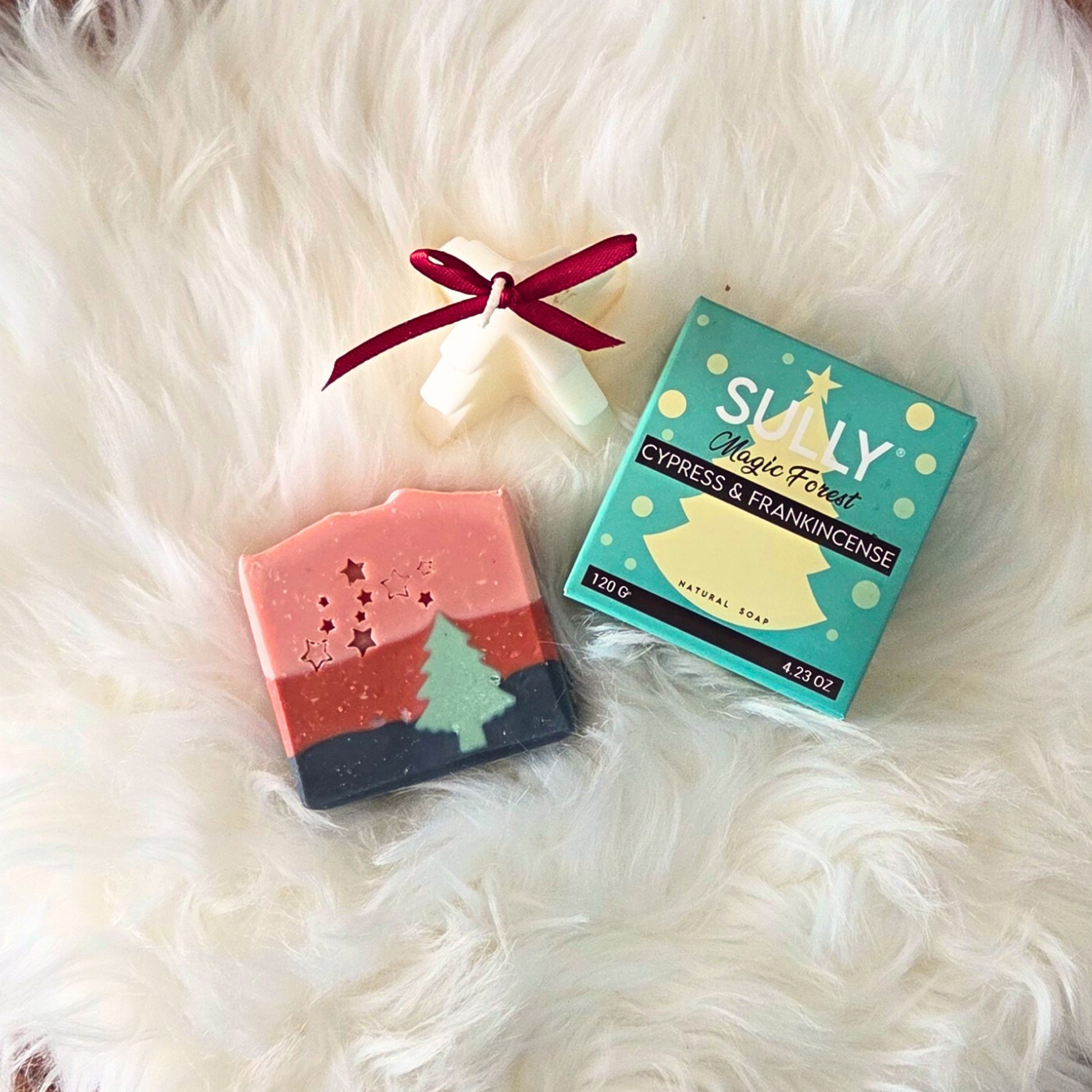 Сапун „Горско вълшебство“ SULLY Naturals с опаковка Cypress & Frankincense, поставен върху бял пухкав фон до коледна свещ.