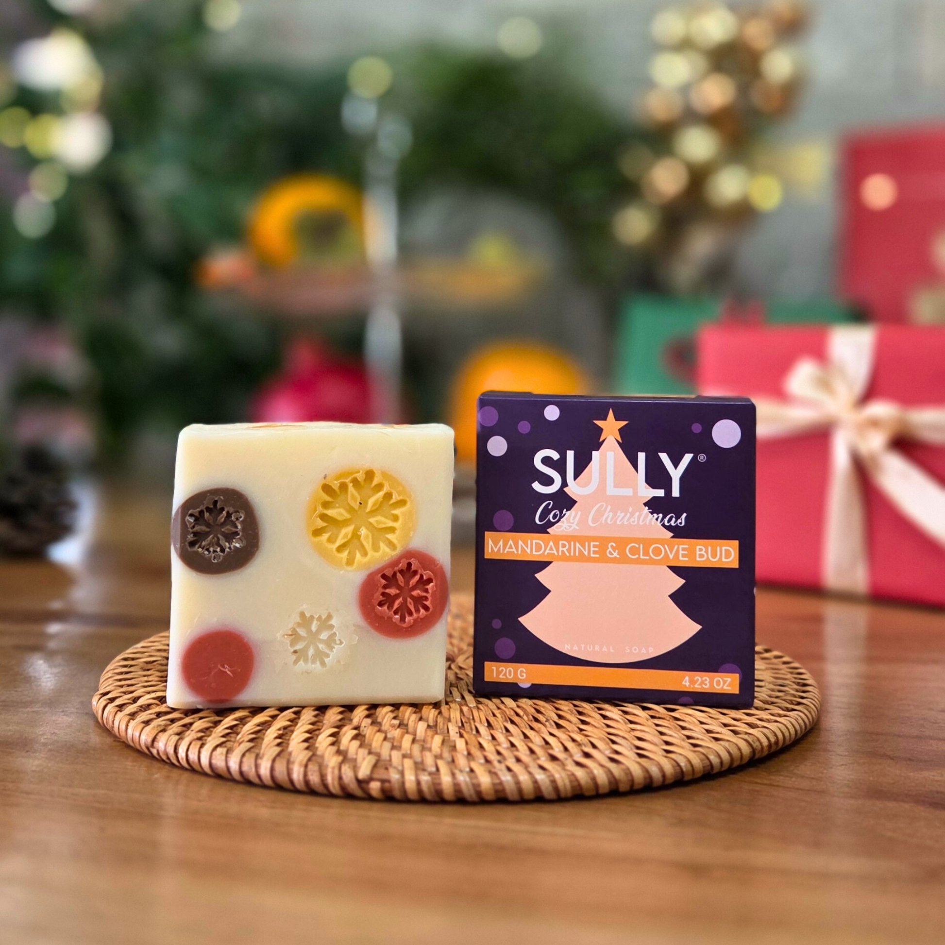 Сапун „Уютна Коледа“ SULLY Naturals с лилава коледна опаковка Mandarine & Clove Bud, върху дървена подложка.