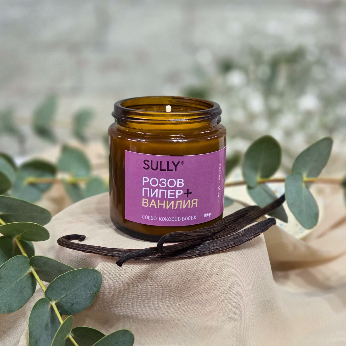 Соева ароматна свещ SULLY „Розов пипер и ванилия“ 80 г върху плат с ванилови шушулки и евкалипт на нежен фон