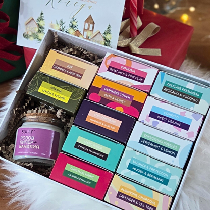 Комплект „12 месеца Ароматна наслада“ от SULLY - цветни сапуни в опаковки, свещ и празнична картичка, подредени красиво за подарък.