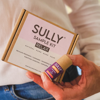 SULLY Sample Kit Relax с мини сапуни и мини балсам за устни 6 г, държани в ръка.