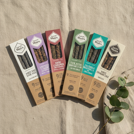 Всички седем натурални ароматни пръчици Sagrada Madre, подредени в лек ветрилообразен ред върху ленен фон с естествена светлина и евкалиптово клонче.